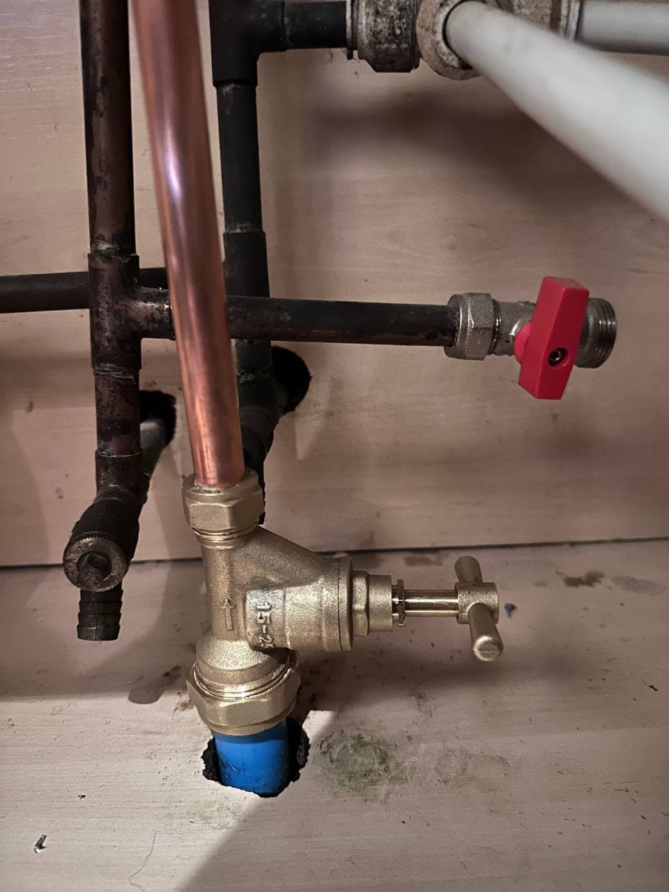 A new brass stopcock and copper pipe connected to the blue incoming water pipe, next to older pipework