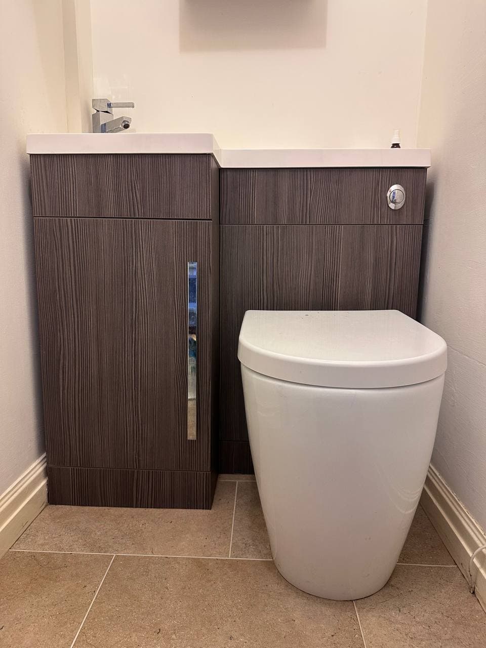 A cloakroom basin and toilet set into a combined wood-effect vanity unit