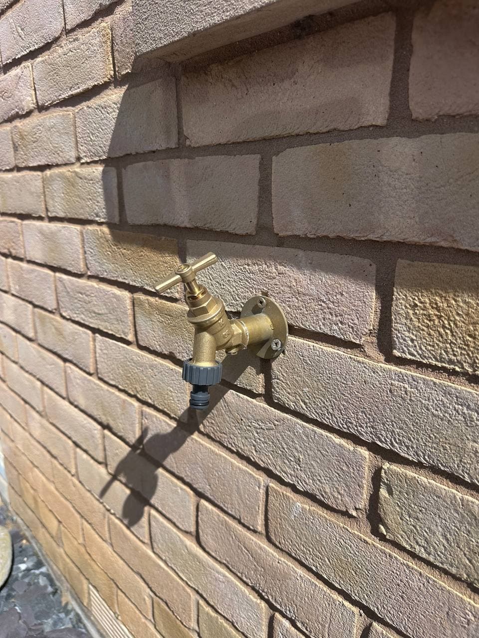 A brass outside tap on a brick wall