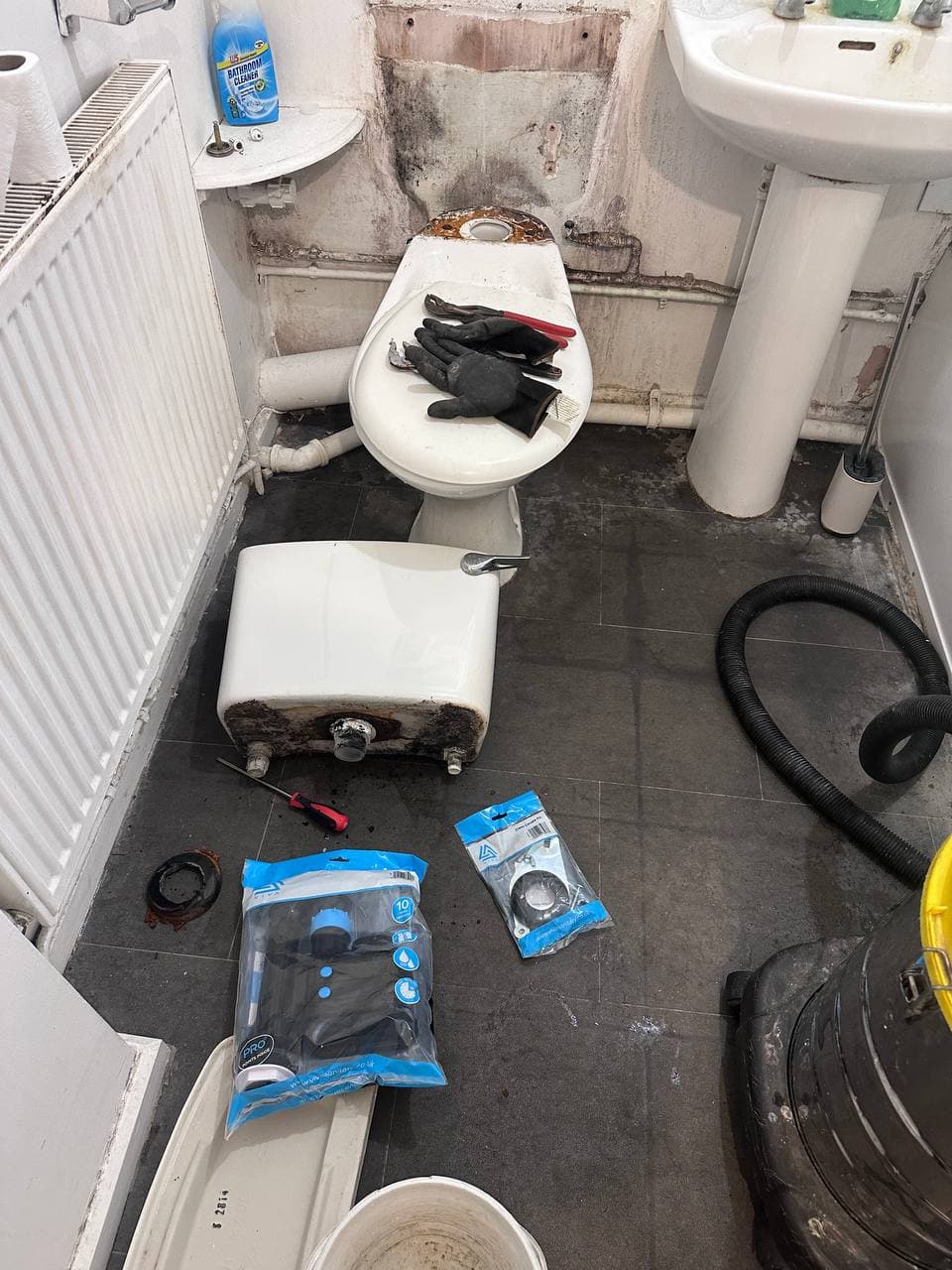 A toilet cistern taken off during a repair, with replacement parts still in their packaging