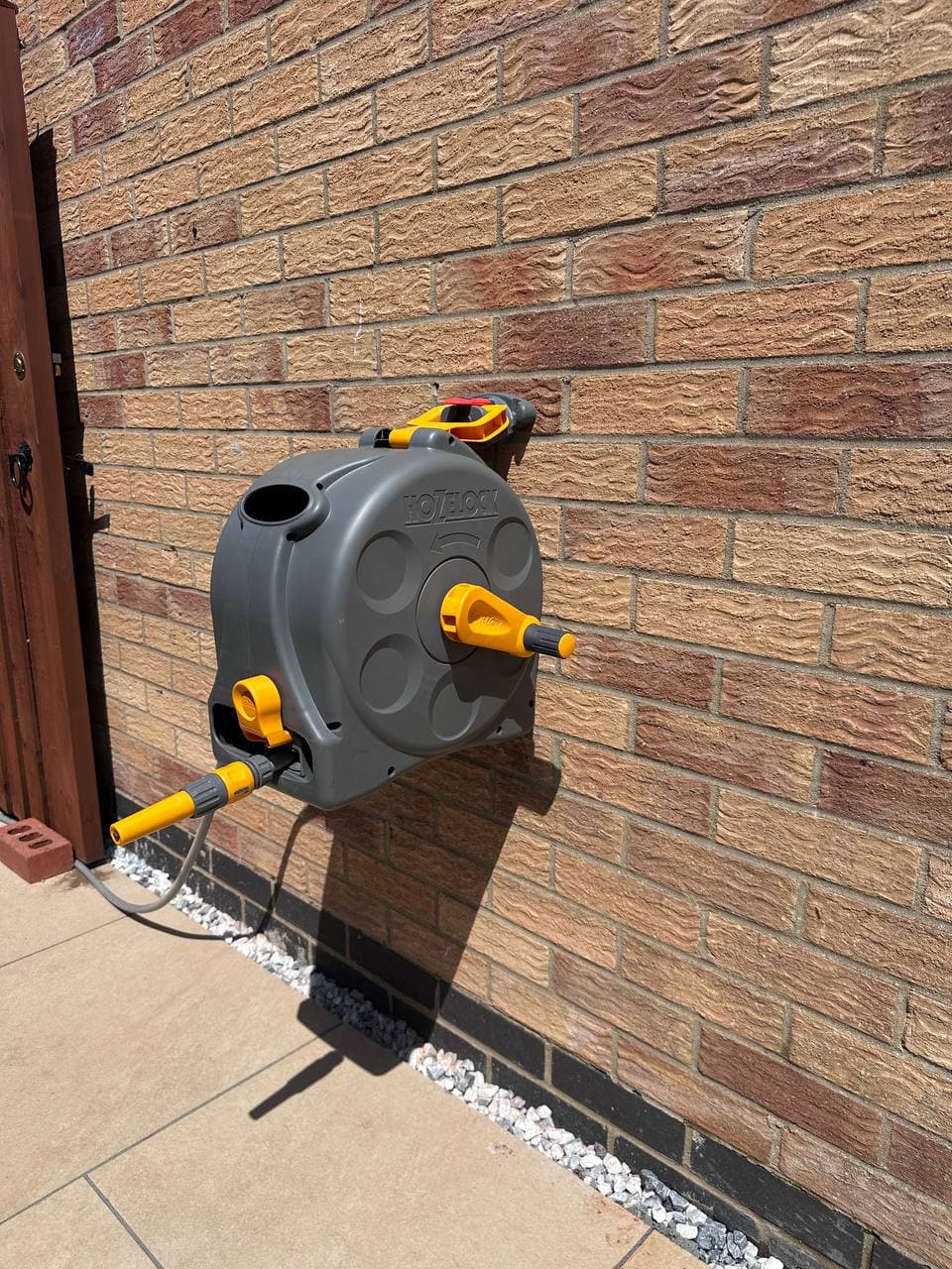 A wall-mounted hose reel on a brick wall