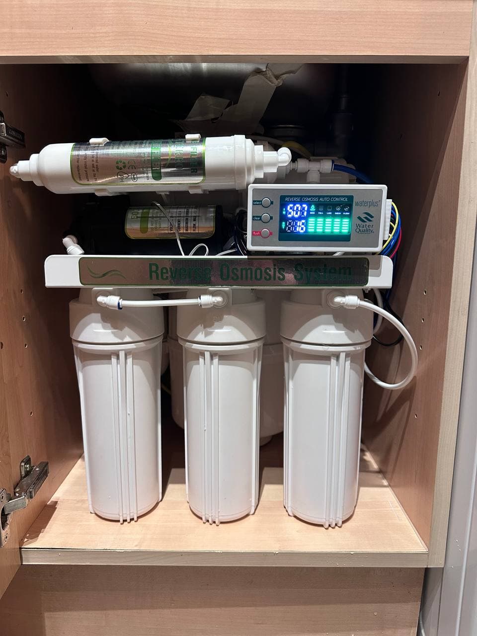 A multi-stage water filter system with a digital display, installed in a kitchen cupboard